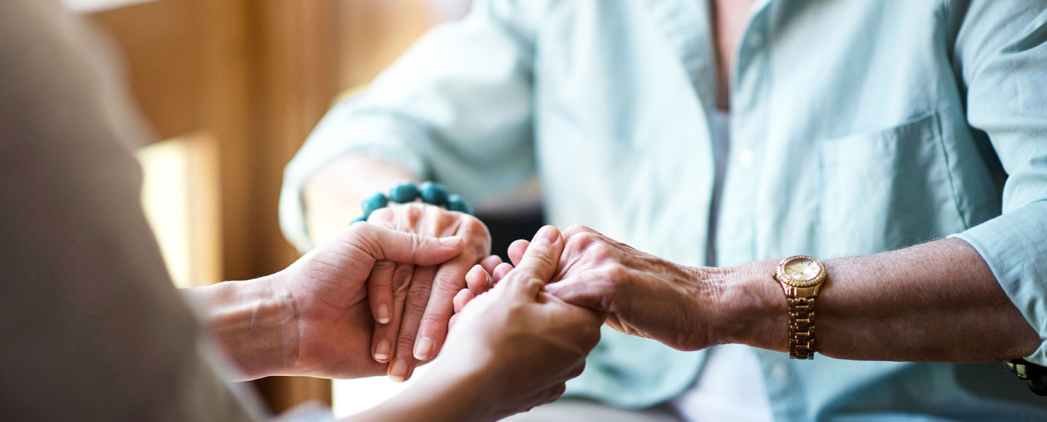 Closeup shot of a young woman holding a senior woman's hands in comfort